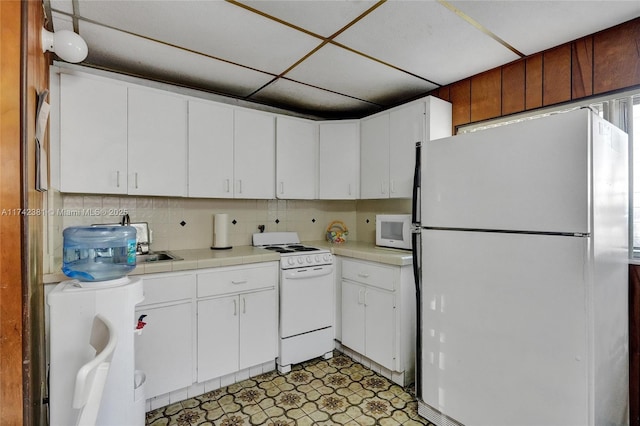 kitchen with white appliances, a paneled ceiling, decorative backsplash, and white cabinets