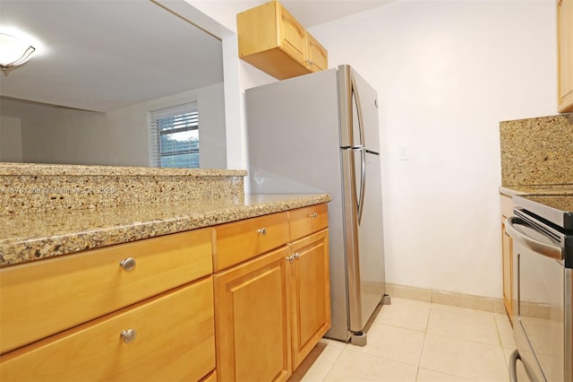 kitchen featuring light stone countertops, stainless steel refrigerator, and stove