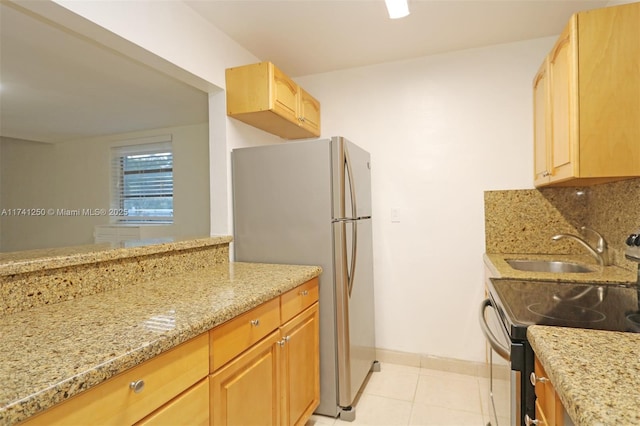 kitchen featuring sink, electric range oven, stainless steel refrigerator, light stone countertops, and decorative backsplash