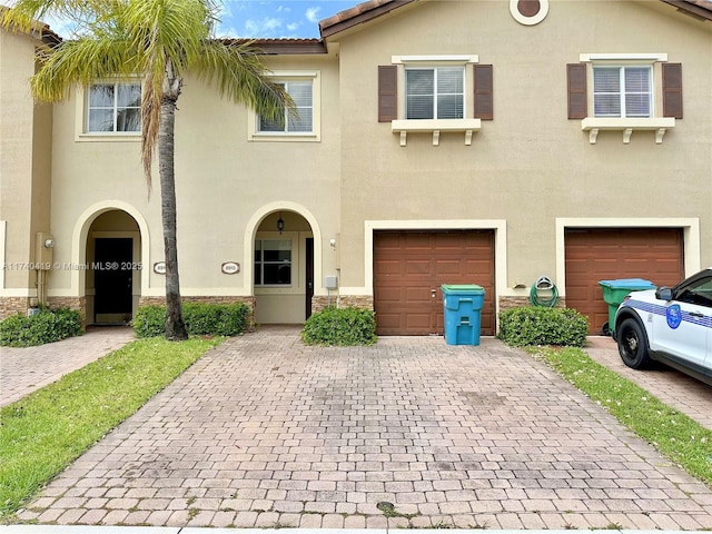 view of front facade with a tiled roof, driveway, stucco siding, and an attached garage