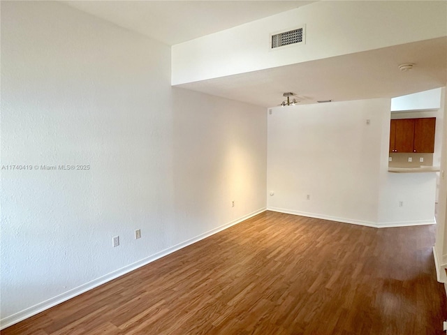 unfurnished room with visible vents, baseboards, and wood finished floors