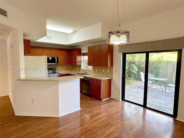 kitchen with light wood-type flooring, brown cabinets, light countertops, and stainless steel appliances