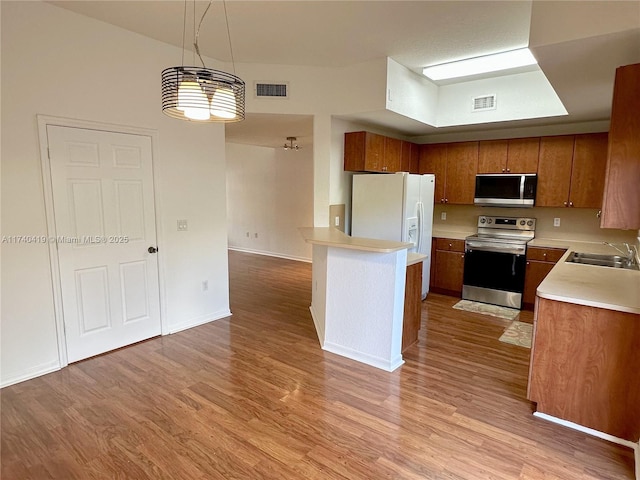 kitchen with a sink, light countertops, brown cabinetry, light wood finished floors, and stainless steel appliances