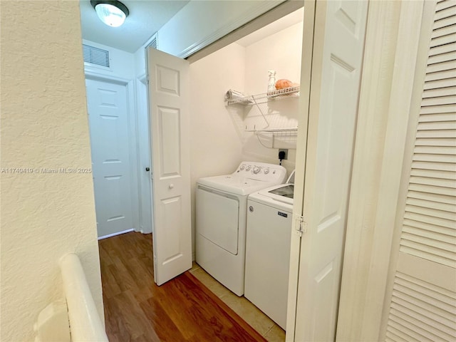 laundry room featuring visible vents, separate washer and dryer, a textured wall, laundry area, and light wood finished floors