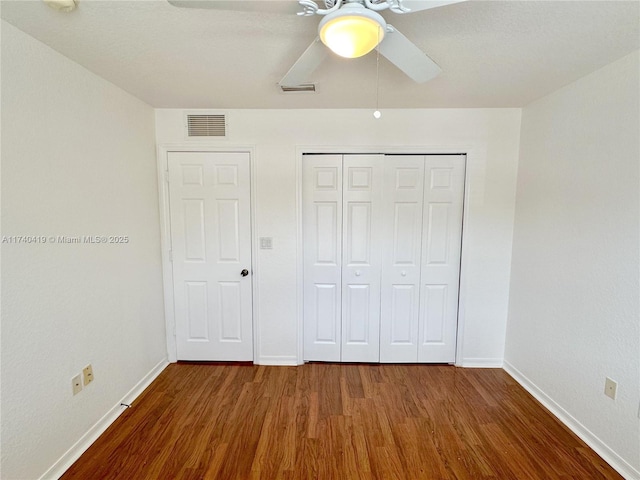 unfurnished bedroom with visible vents, baseboards, a closet, and wood finished floors