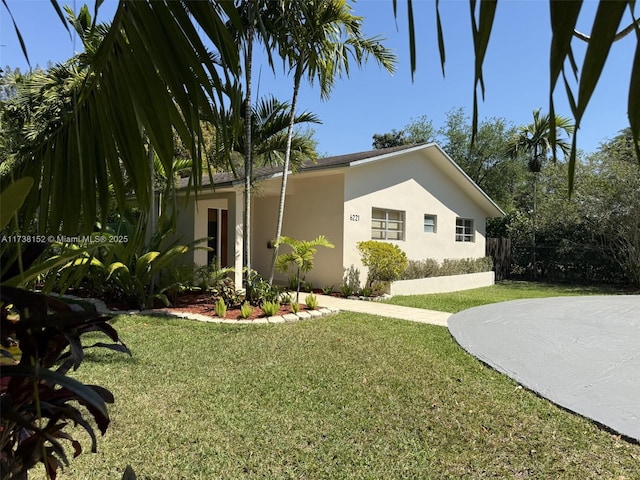 exterior space featuring a front yard, fence, and stucco siding