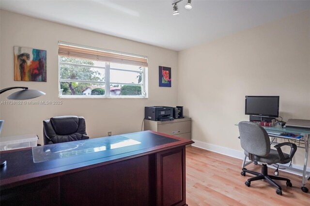 office area with rail lighting and light wood-type flooring