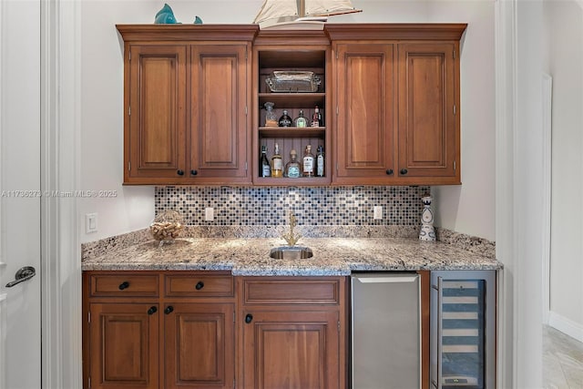 bar with sink, light stone counters, beverage cooler, and backsplash