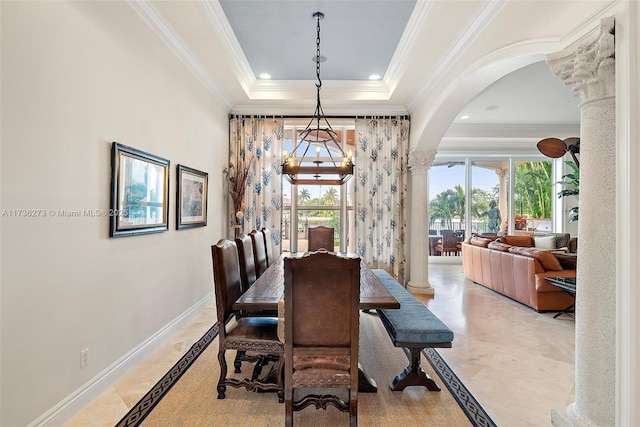 dining room featuring a tray ceiling, ornamental molding, and decorative columns