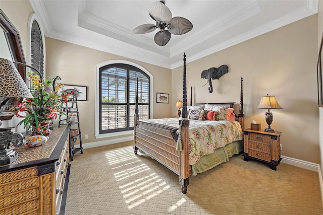 carpeted bedroom featuring a tray ceiling, ornamental molding, and ceiling fan