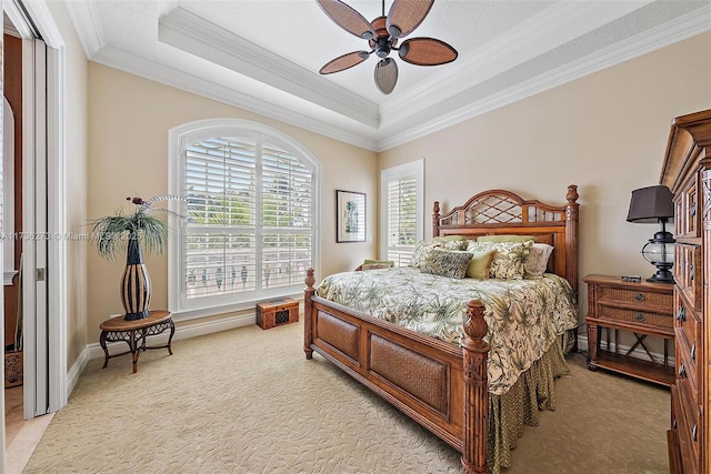 bedroom featuring a raised ceiling, crown molding, light carpet, and ceiling fan