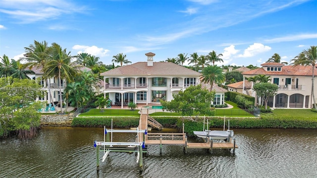 back of property with a balcony, a water view, and a yard