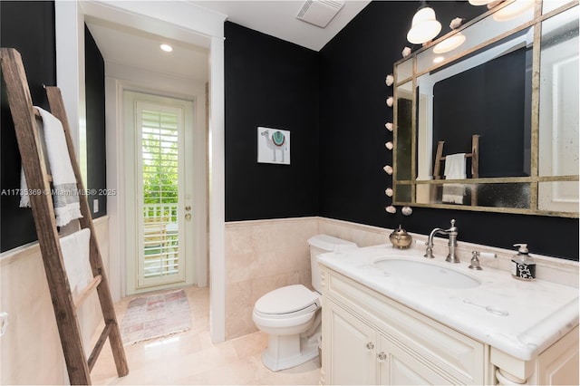 bathroom with tile patterned floors, vanity, toilet, and tile walls