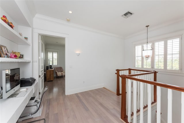 corridor with crown molding, an inviting chandelier, and light hardwood / wood-style flooring