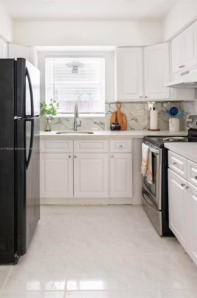 2260 Charleston St, Hollywood, FL 33020 - kitchen with electric stove, sink, white cabinetry, black refrigerator, and backsplash
