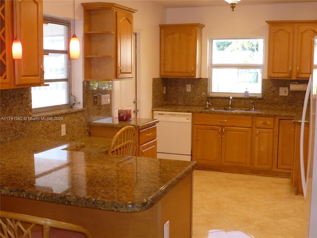 kitchen featuring sink, decorative light fixtures, kitchen peninsula, white appliances, and a healthy amount of sunlight