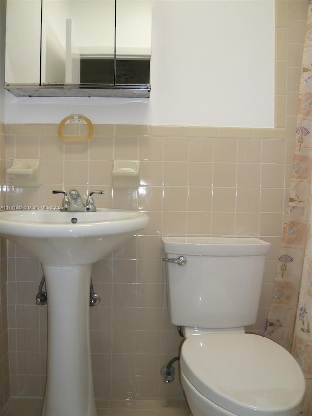 bathroom featuring sink, tile walls, and toilet