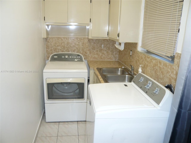 washroom with cabinets, light tile patterned flooring, sink, and washing machine and clothes dryer