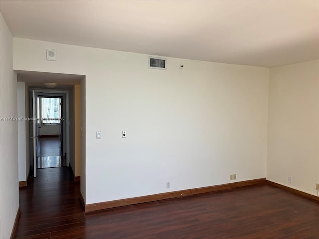 unfurnished room with dark wood-type flooring, visible vents, and baseboards