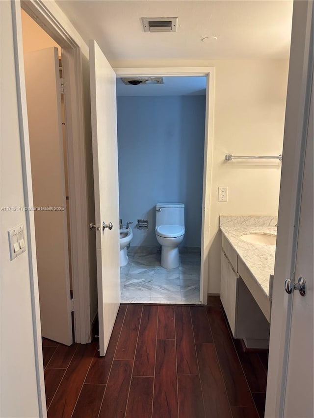 bathroom featuring visible vents, toilet, vanity, a bidet, and wood finish floors