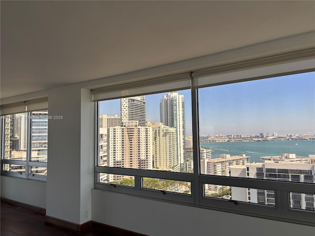 interior space with a view of city, a water view, and baseboards