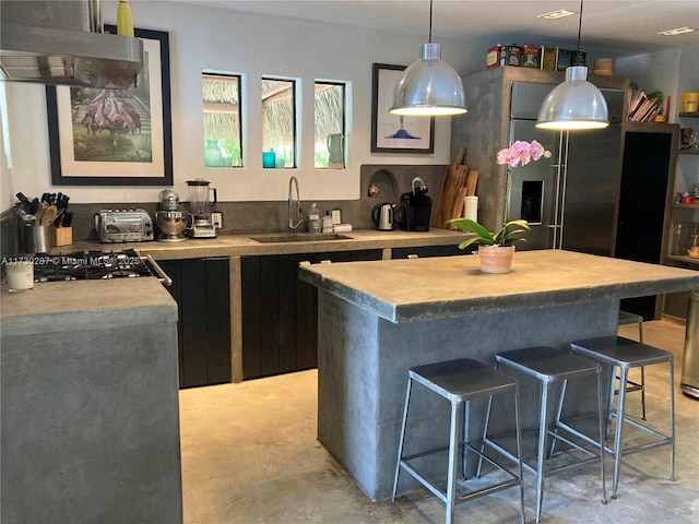 kitchen featuring sink, a center island, decorative light fixtures, exhaust hood, and stainless steel gas stovetop