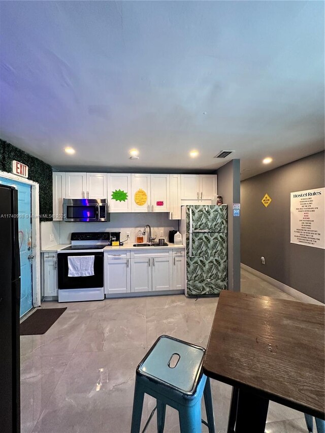 5895 NW 12th Ave, Miami, FL 33127 - kitchen with sink, refrigerator, white cabinetry, electric range oven, and black fridge
