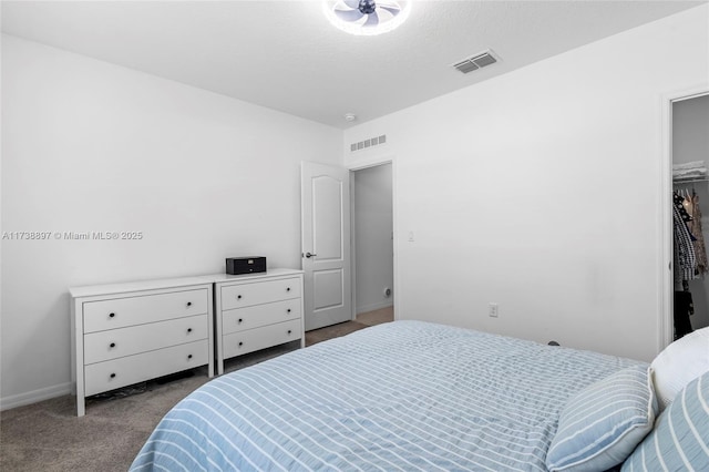 carpeted bedroom featuring a walk in closet and a textured ceiling