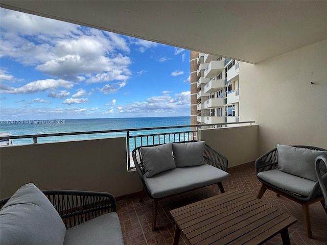 balcony featuring a water view, an outdoor hangout area, and a view of the beach