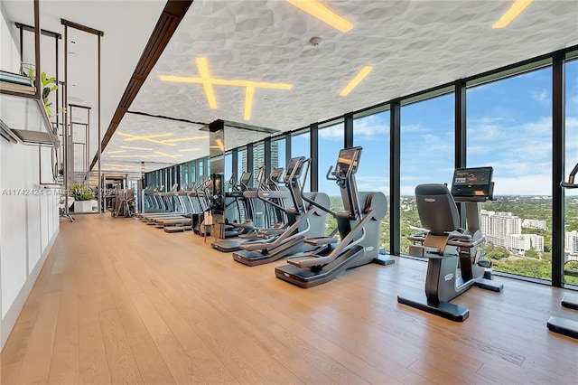 exercise room featuring hardwood / wood-style flooring, floor to ceiling windows, and a textured ceiling