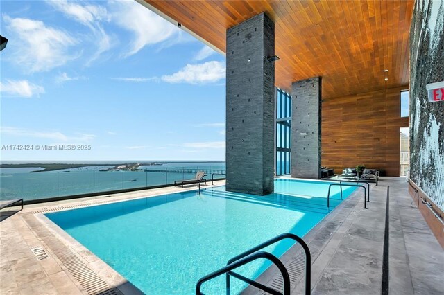 view of swimming pool featuring a water view and a patio area