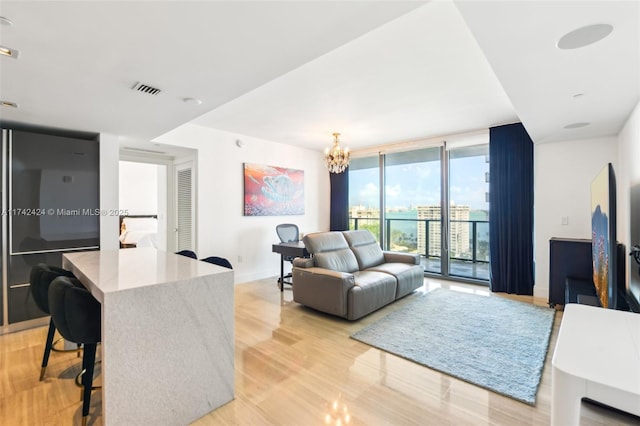 living room featuring a wall of windows, light hardwood / wood-style flooring, and an inviting chandelier