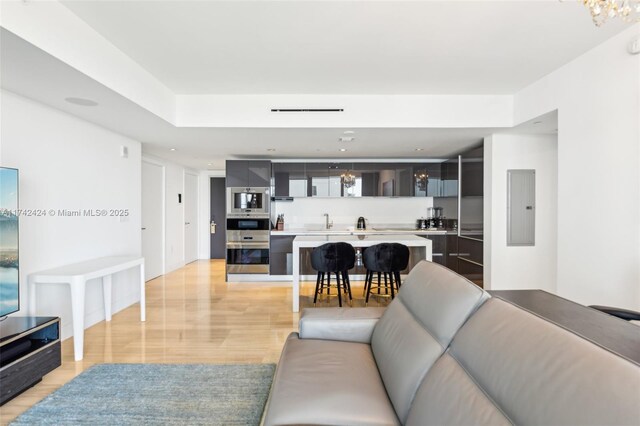 living room featuring sink, electric panel, and light hardwood / wood-style flooring