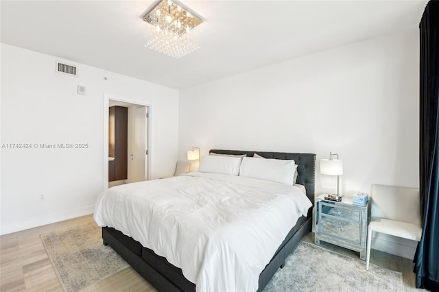 bedroom with light wood-type flooring and an inviting chandelier