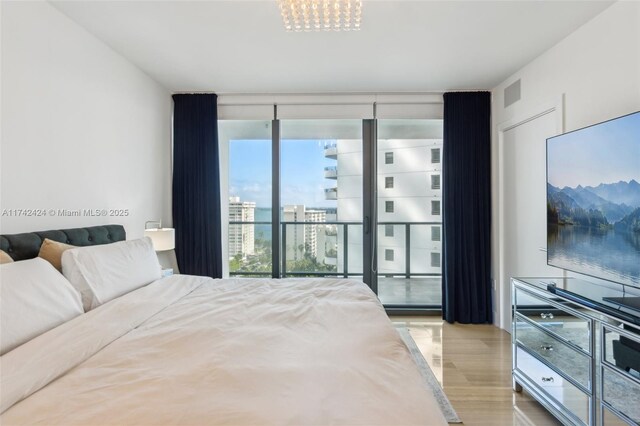 bedroom featuring light wood-type flooring and a wall of windows