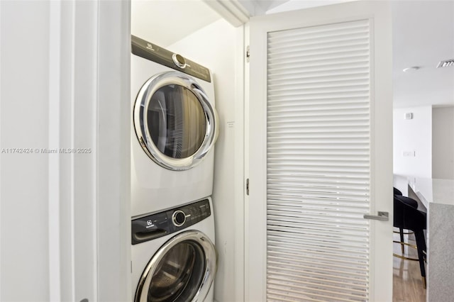 laundry room with stacked washer / dryer and hardwood / wood-style floors