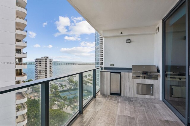 balcony featuring a water view, exterior kitchen, and grilling area