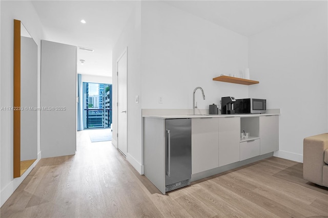 kitchen with sink, light hardwood / wood-style flooring, white cabinets, and appliances with stainless steel finishes