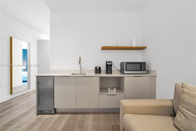 kitchen with sink, gray cabinetry, light hardwood / wood-style floors, and kitchen peninsula