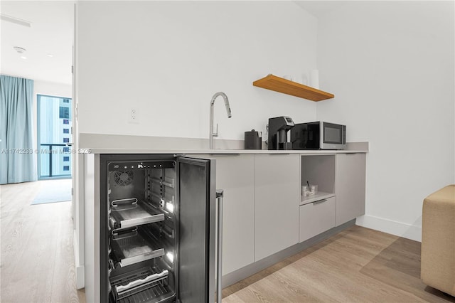 kitchen with wine cooler, sink, and light wood-type flooring