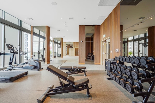 gym with a healthy amount of sunlight, a wall of windows, and wood walls