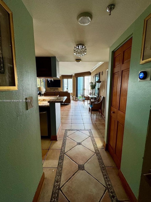 corridor with crown molding, a textured ceiling, and light tile patterned floors