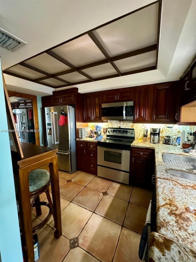 kitchen featuring sink, light tile patterned floors, appliances with stainless steel finishes, light stone counters, and tasteful backsplash