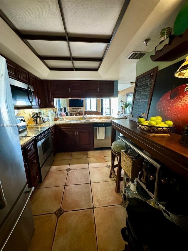 kitchen with dark brown cabinetry, sink, light tile patterned floors, kitchen peninsula, and stainless steel appliances