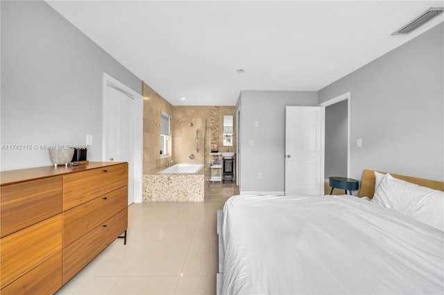 bedroom featuring ensuite bathroom and light tile patterned floors