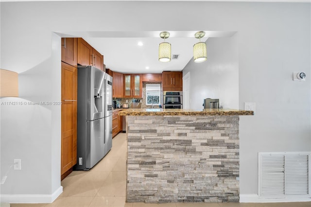 kitchen with light tile patterned flooring, stone countertops, appliances with stainless steel finishes, kitchen peninsula, and pendant lighting