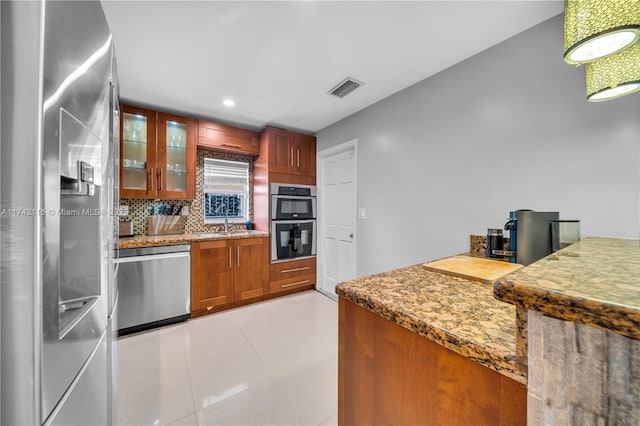 kitchen with sink, tasteful backsplash, stone countertops, light tile patterned floors, and stainless steel appliances