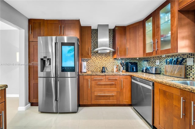 kitchen with light stone counters, backsplash, stainless steel appliances, and wall chimney exhaust hood