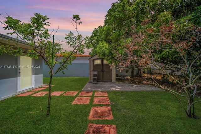 yard at dusk with a storage shed and a patio