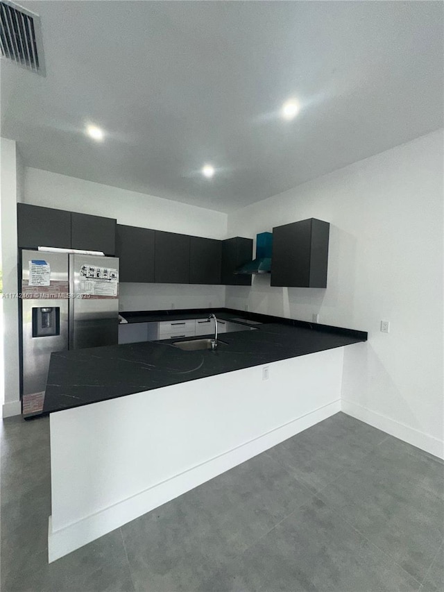 kitchen featuring sink, kitchen peninsula, wall chimney exhaust hood, and stainless steel refrigerator with ice dispenser